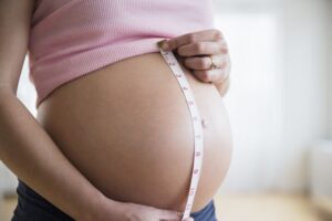 mid-section-of-pregnant-woman-measuring-her-belly for changes in her body